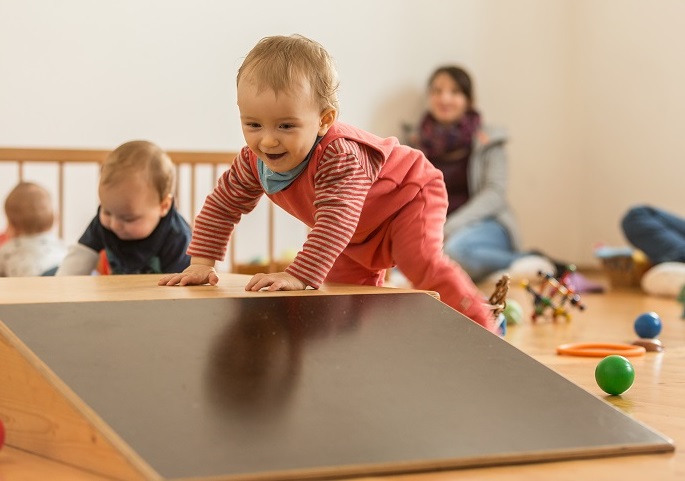 Baby stützt sich auf Podest und steht auf